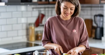 Person wearing a branded T-shirt is chopping vegetables