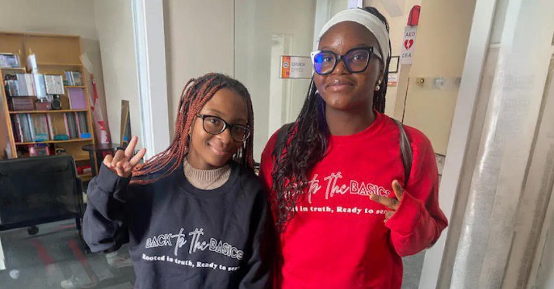 Two smiling youth wearing matching branded sweatshirts.