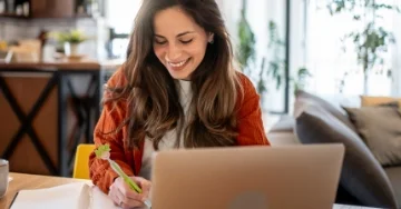Smiling person writing in a notebook using a MopTopper pen.
