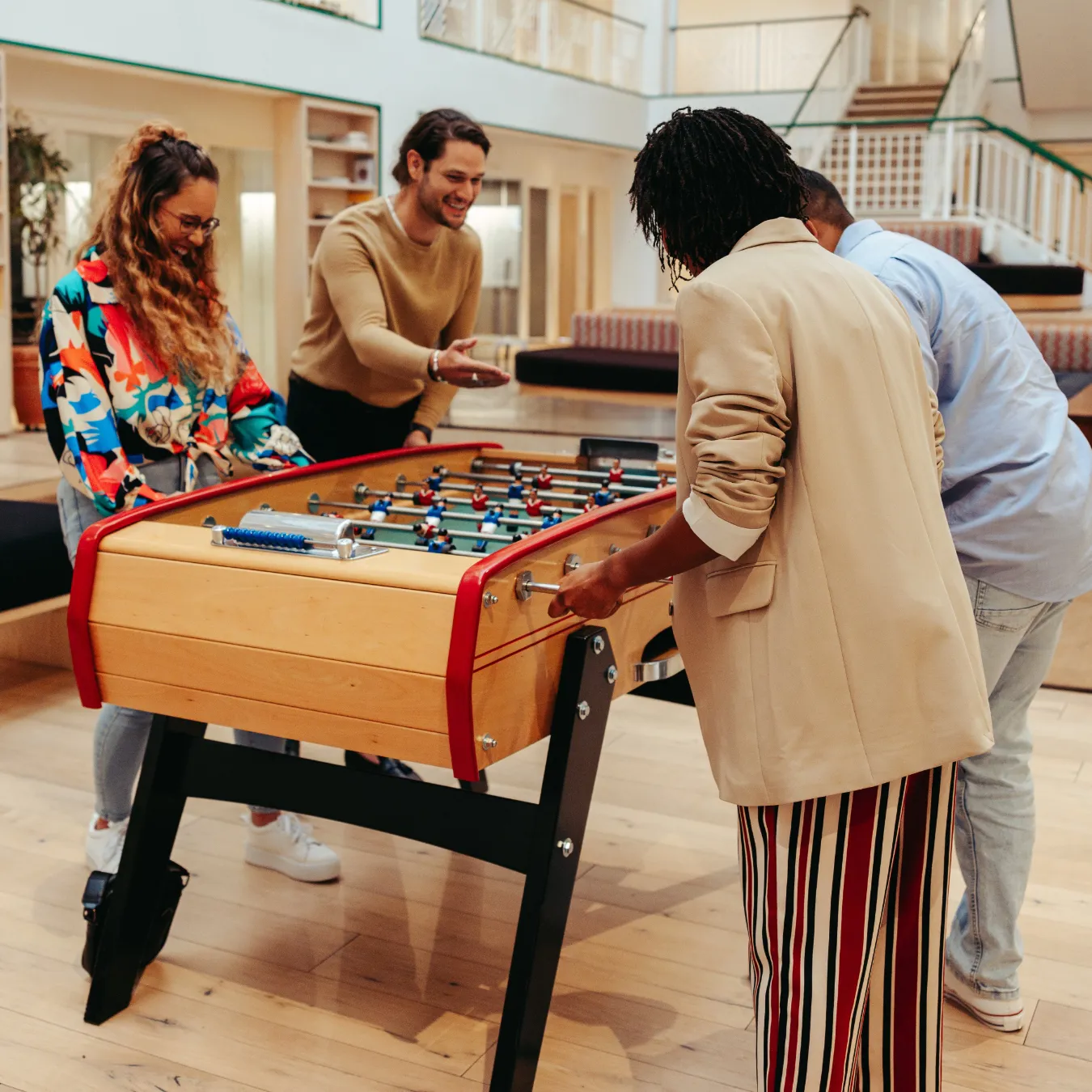 Group of teammates playing a game of foosball in an office setting.