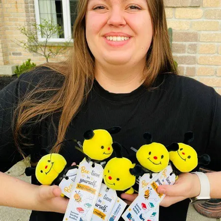 Smiling person with arms full of plush animal bees.