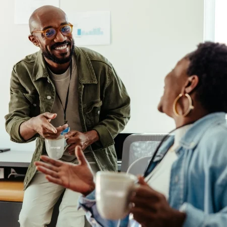 Two co-workers laughing during a coffee break.
