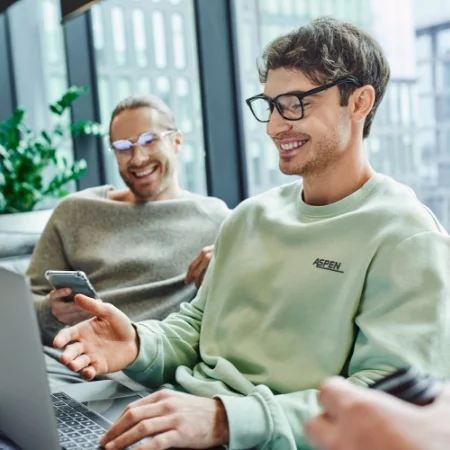 Two casually dressed employees looking at a laptop.