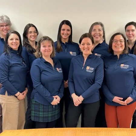 Team of smiling university staff dressed in branded blue pullovers.