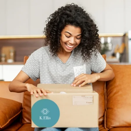 Person sitting on their couch at home opening a branded promotional box.