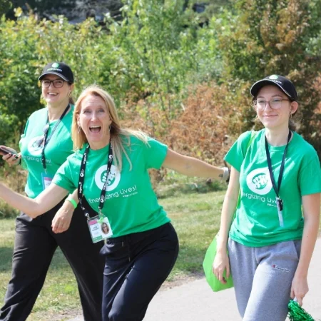 Three smiling people wearing branded T-shirt are participating in a charity walk event.