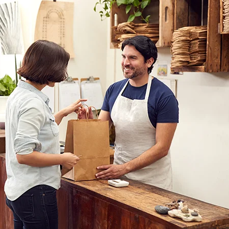 An employee checking out a customer with a paper bag