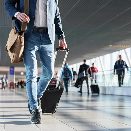 A man in an airport with two pieces of luggage