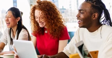 Group of smiling and laughing students together at a table.
