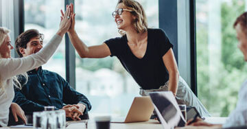 Teammates high fiving at work