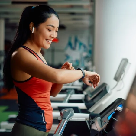 Person using their smart watch while running on a treadmill.