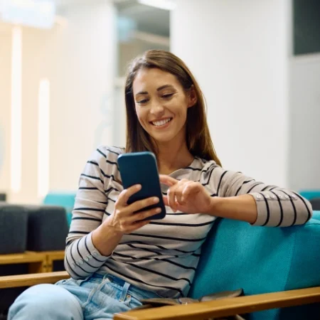 Person sitting in a waiting room scrolling on their phone.