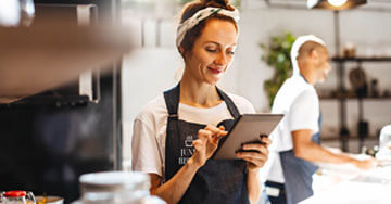 Restaurant owner behind the counter working on a tablet