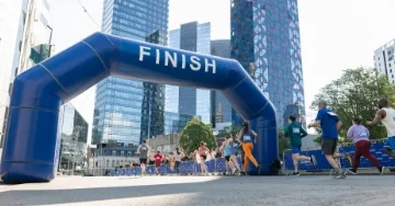 Group of people running across a race finish line.