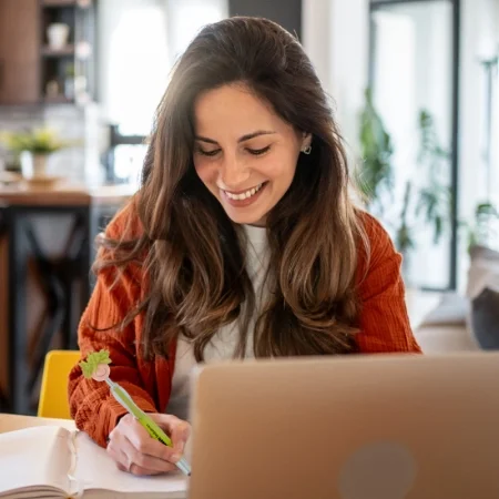 Smiling person writing in a notebook using a MopTopper pen.
