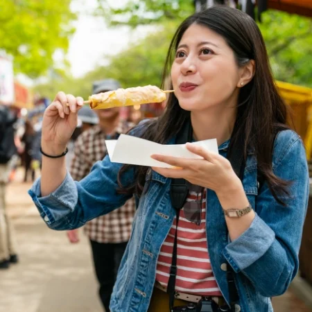 Person eating street food at a carnival.