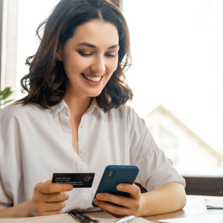 person looking at a credit card while typing on a phone