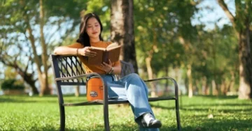 Person sitting on a bench in the park reading a book in the spring.