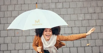 Smiling person under an umbrella in the rain.