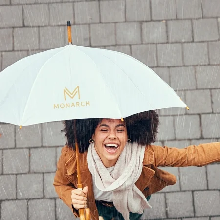 Smiling person under an umbrella in the rain.