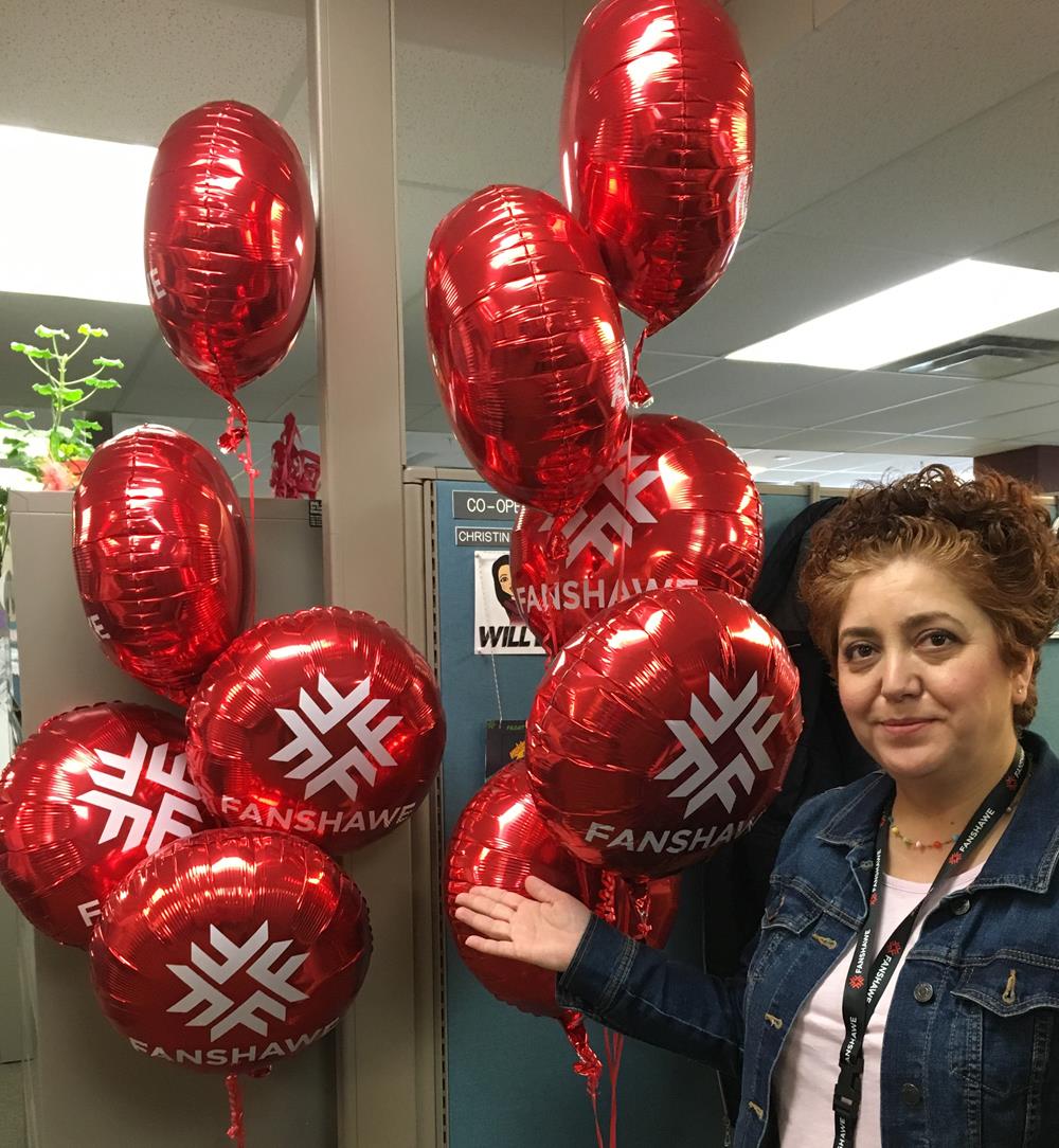 a woman standing next to a bunch of red balloons