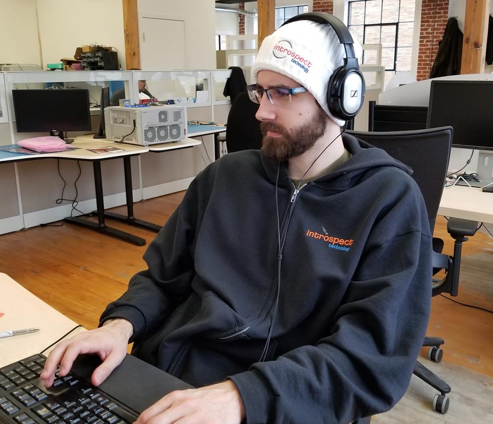 a man wearing headphones and a black sweatshirt sitting at a desk