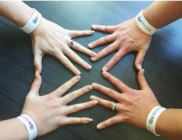 a group of hands with white wristbands on them