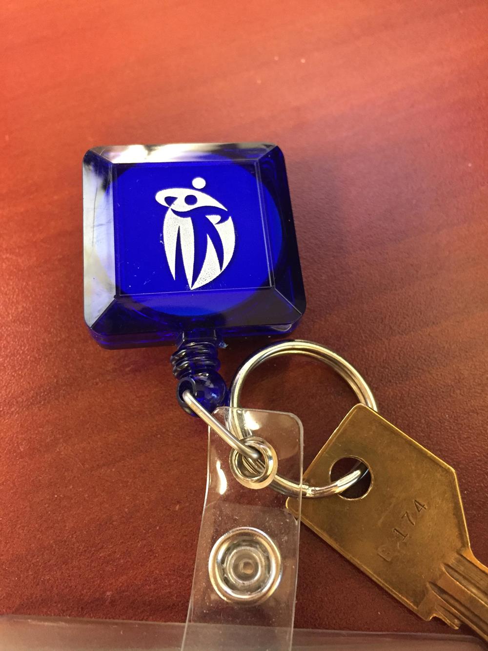 a key chain with a blue square with a white logo on it