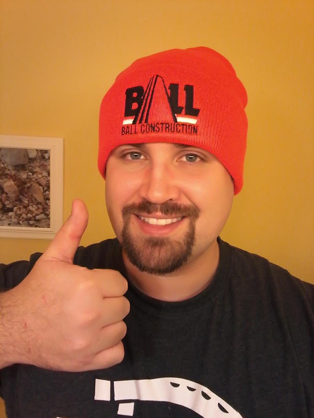 a man wearing a beanie and giving a thumbs up