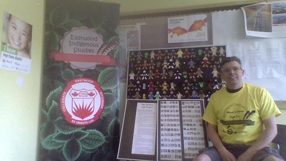 Customer photo from Greg of our Economy Retractable Banner Display - 31-1/2", a man sitting in front of a display of small paper dolls