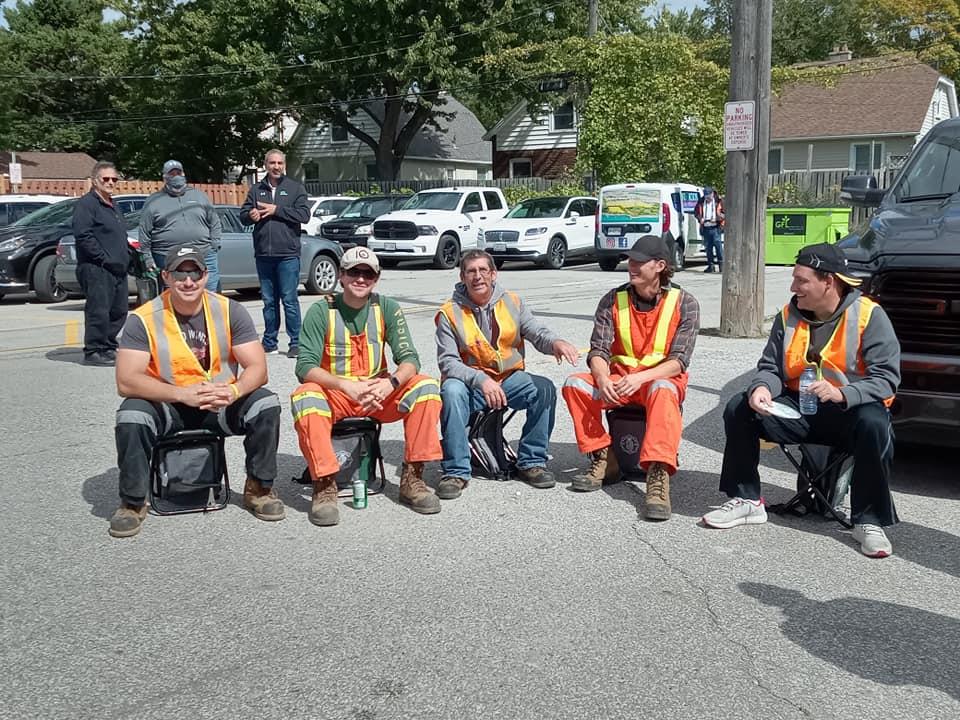 a group of men in orange vests and reflective vests sitting on the street