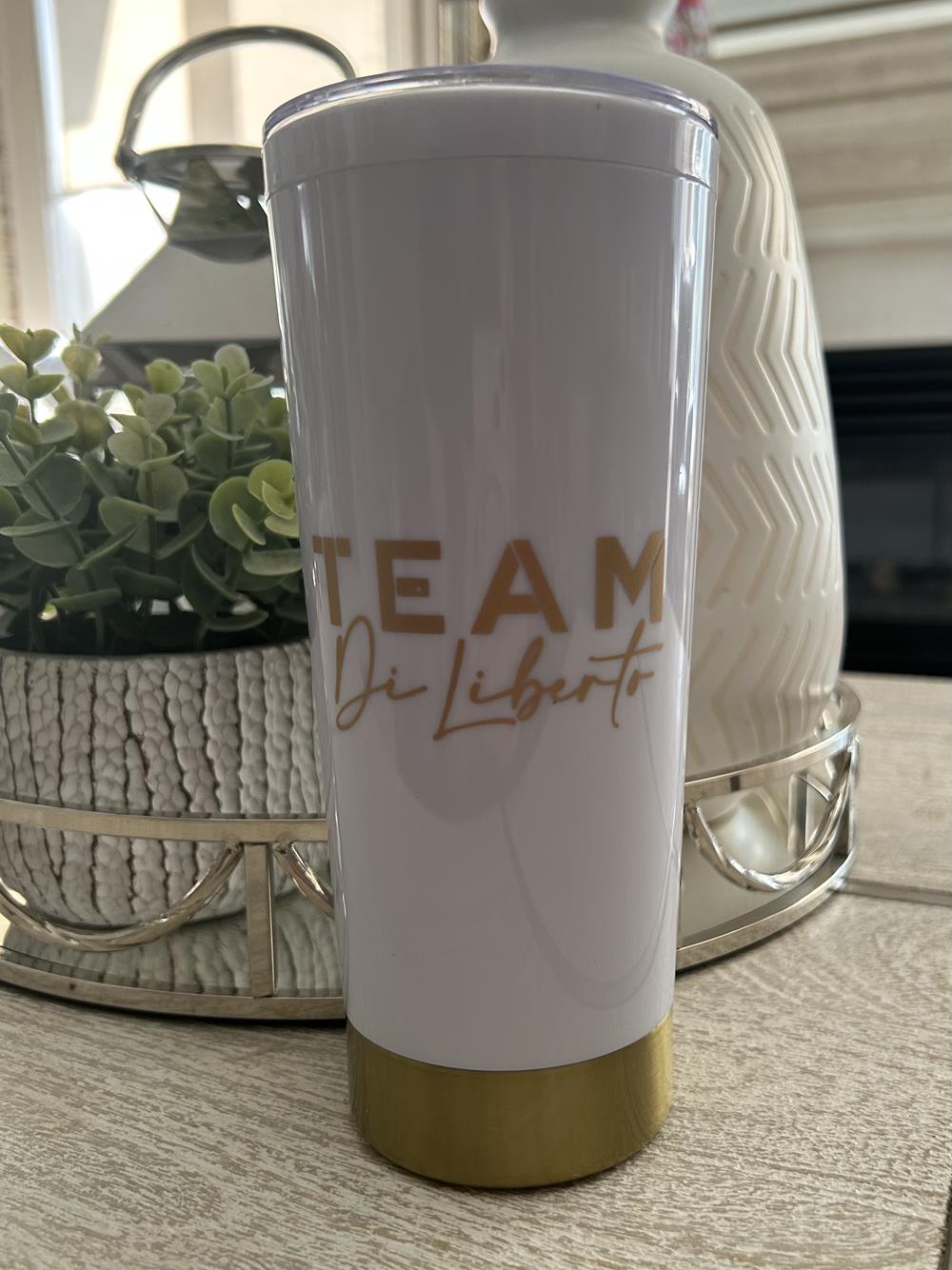 a white and gold tumbler with gold text