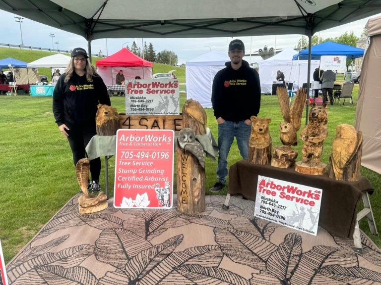 a couple of people standing next to a wood carving