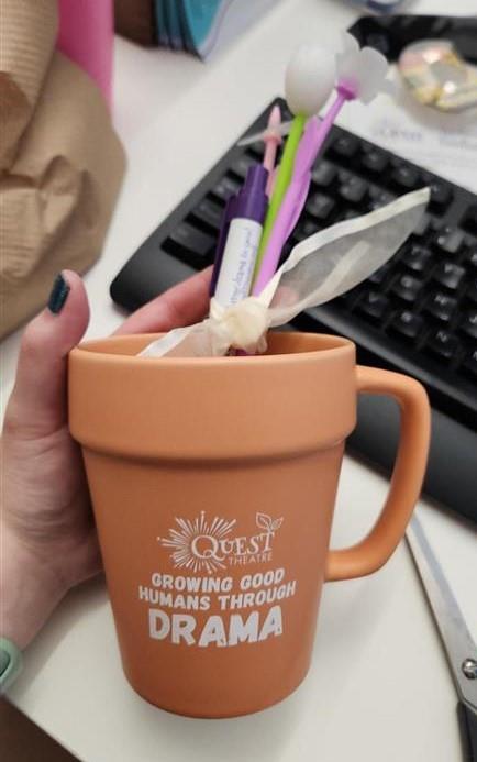 Customer photo from Helena of our Flower Pot Mug - 14 oz., a hand holding a cup with a pen and other objects in the background