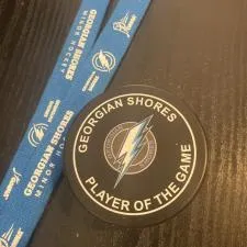 Customer photo from Keith of our Hockey Puck, a black round object next to a blue lanyard